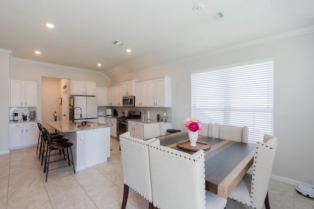 kitchen with appliances with stainless steel finishes, white cabinets, an island with sink, and a kitchen bar