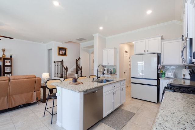 kitchen featuring open floor plan, appliances with stainless steel finishes, a sink, and white cabinets