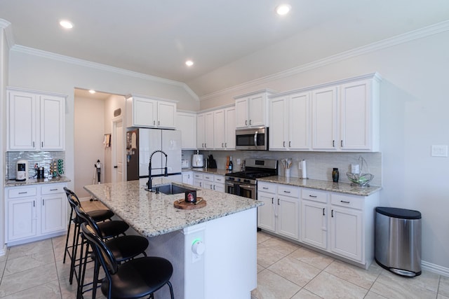 kitchen with stainless steel appliances, white cabinets, a sink, and a breakfast bar area