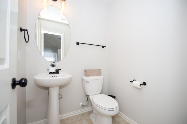 half bathroom featuring tile patterned flooring, baseboards, and toilet