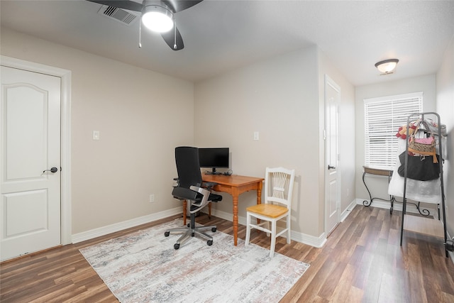 office space with baseboards, visible vents, and wood finished floors