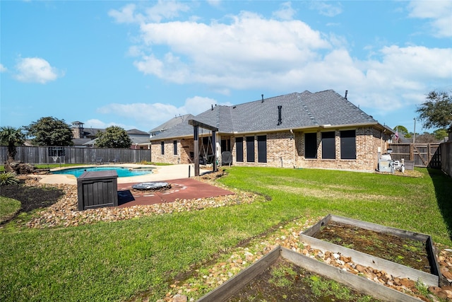 back of property featuring brick siding, a yard, a vegetable garden, a patio area, and a fenced backyard