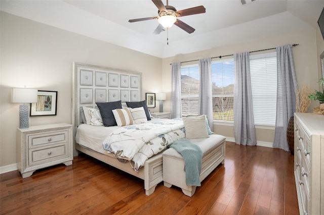 bedroom featuring a ceiling fan, visible vents, baseboards, hardwood / wood-style floors, and a raised ceiling