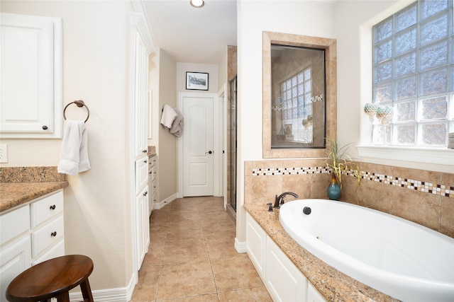 full bath featuring a stall shower, baseboards, a garden tub, tile patterned flooring, and vanity