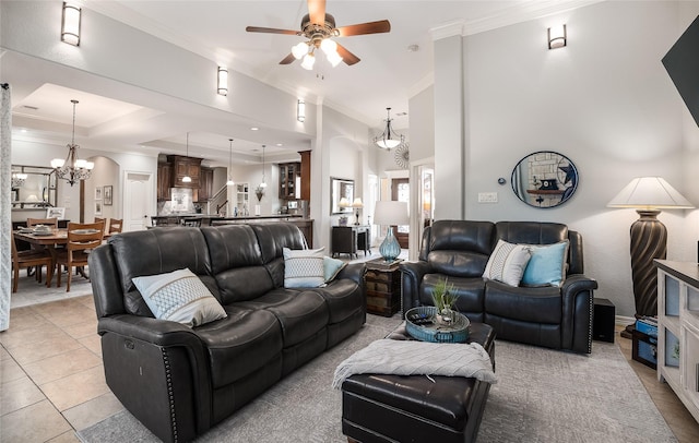 living area featuring light tile patterned floors, ceiling fan with notable chandelier, a towering ceiling, stairs, and crown molding