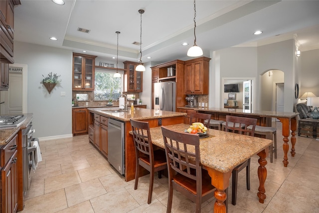 kitchen featuring appliances with stainless steel finishes, a breakfast bar, a raised ceiling, and a sink