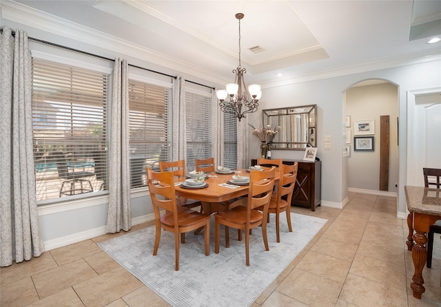 dining area featuring arched walkways, a raised ceiling, ornamental molding, light tile patterned flooring, and baseboards