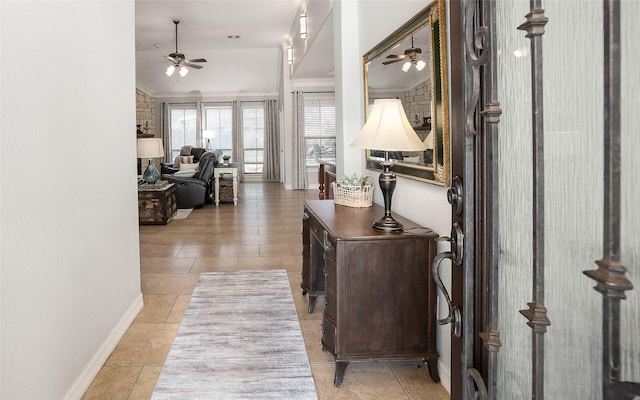 hallway with light tile patterned floors, baseboards, and ornamental molding