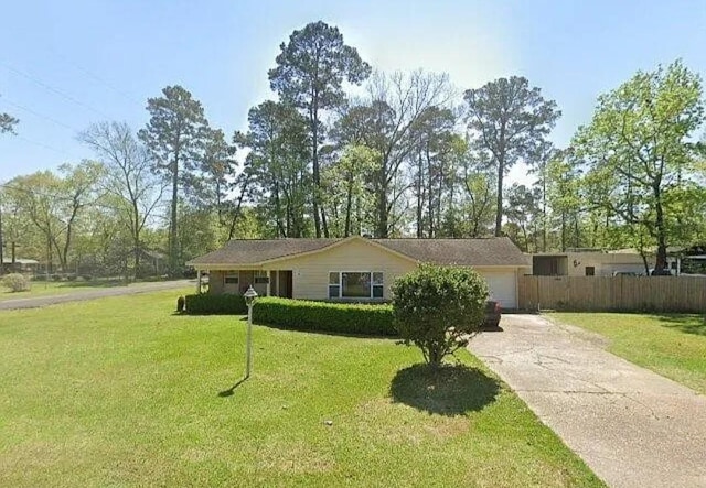 ranch-style home featuring an attached garage, driveway, a front lawn, and fence