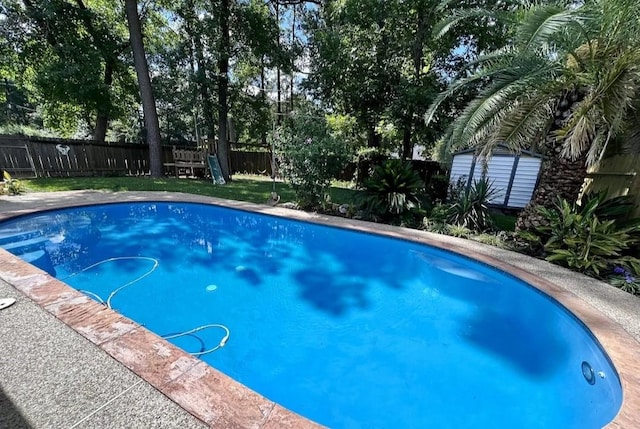 view of pool featuring a fenced backyard, a storage unit, and an outdoor structure