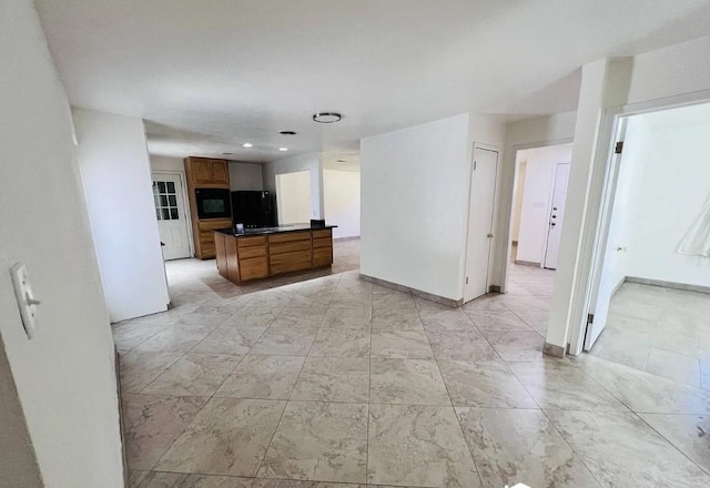 kitchen with wall oven, refrigerator, baseboards, brown cabinetry, and dark countertops