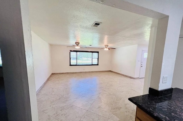 empty room featuring baseboards, visible vents, ceiling fan, and a textured ceiling