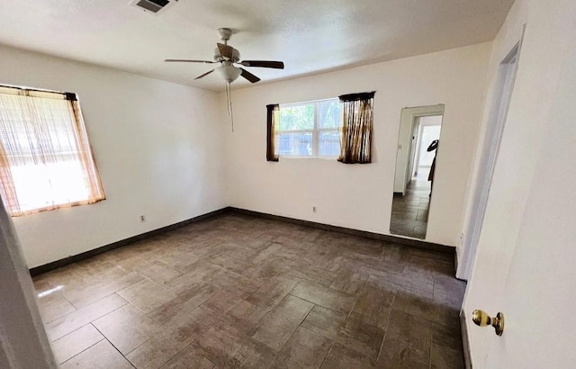 unfurnished room featuring a ceiling fan, visible vents, and baseboards