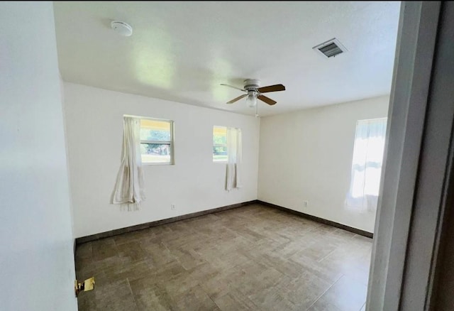 spare room with visible vents, ceiling fan, and baseboards