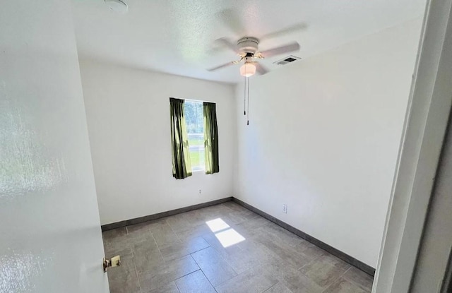 empty room featuring baseboards, visible vents, and ceiling fan