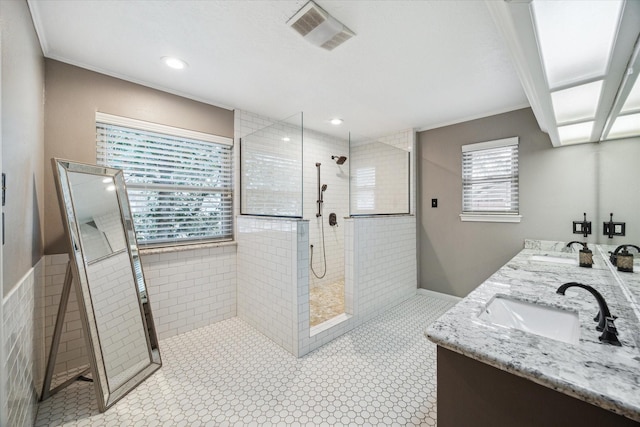 full bathroom with double vanity, visible vents, a sink, and a walk in shower