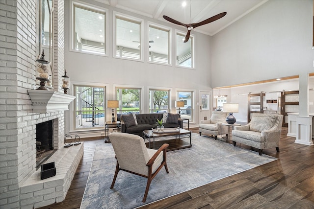 living area featuring beamed ceiling, a fireplace, dark wood finished floors, and crown molding