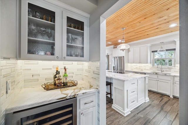 kitchen featuring beverage cooler, wood ceiling, light stone countertops, stainless steel refrigerator with ice dispenser, and a sink