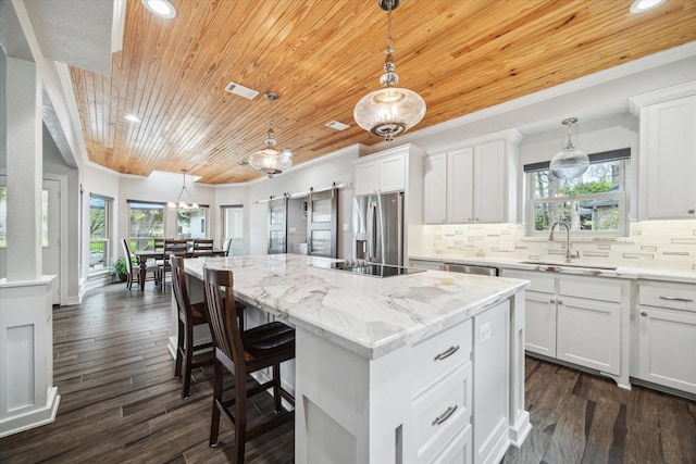 kitchen featuring stainless steel appliances, visible vents, backsplash, a sink, and an island with sink