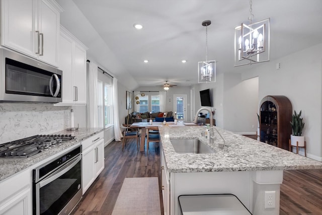 kitchen featuring dark wood-type flooring, a sink, tasteful backsplash, open floor plan, and stainless steel appliances