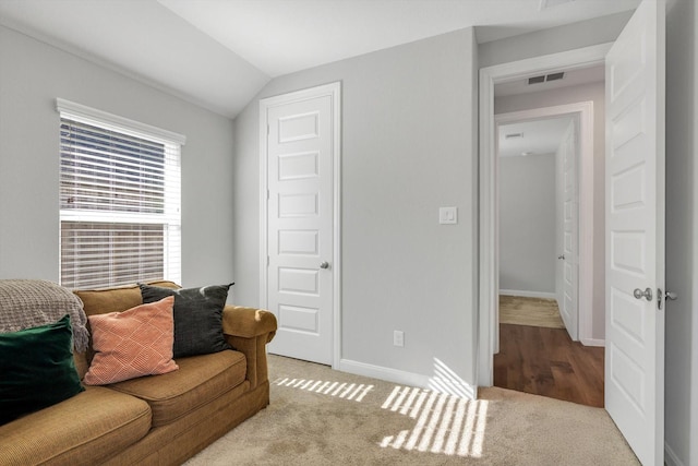 carpeted living room with visible vents, baseboards, and vaulted ceiling