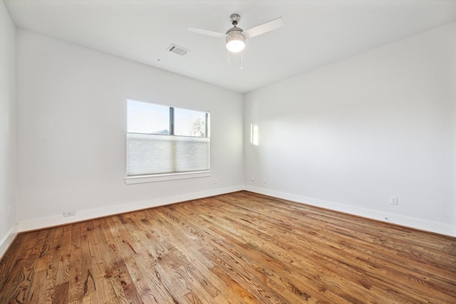 empty room featuring ceiling fan, wood finished floors, visible vents, and baseboards