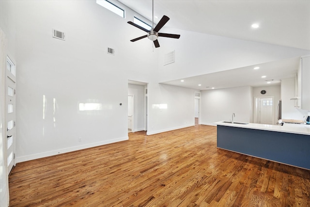 unfurnished living room with light wood-style floors, visible vents, and a sink