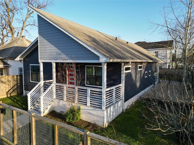 view of front of house featuring roof with shingles and fence