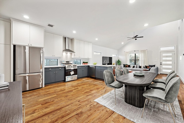 kitchen with visible vents, gray cabinets, white cabinets, appliances with stainless steel finishes, and wall chimney exhaust hood