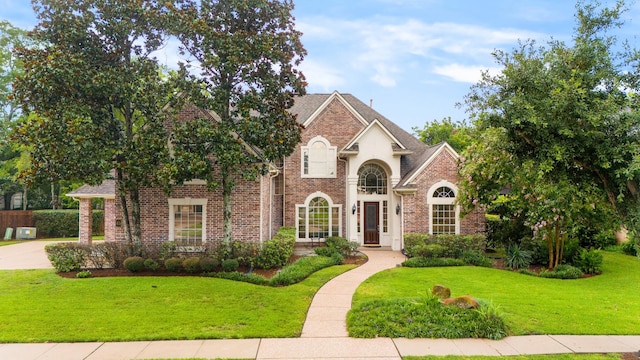 view of front of house featuring brick siding, a front yard, and a shingled roof