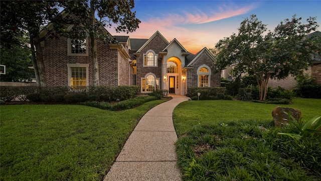 french country home with brick siding and a lawn