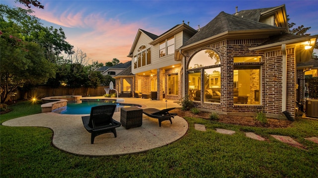 back of property at dusk with a fenced in pool, brick siding, a patio, an in ground hot tub, and a fenced backyard