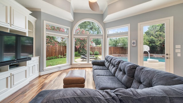 living area with ornamental molding, light wood-style floors, and ceiling fan