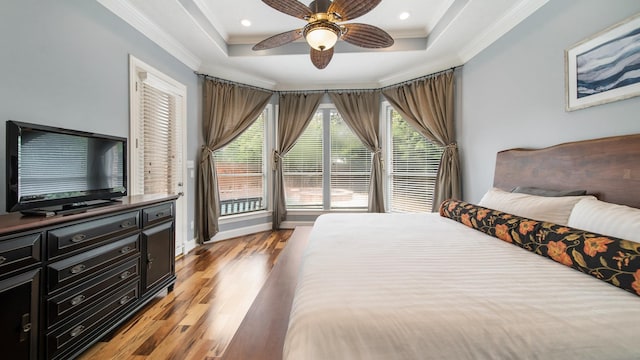 bedroom with multiple windows, a raised ceiling, and crown molding