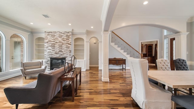 dining room with a tile fireplace, wood finished floors, built in features, and ornate columns