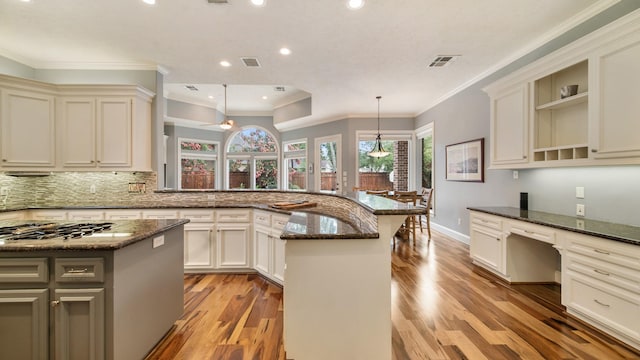 kitchen featuring a peninsula, visible vents, built in study area, open shelves, and dark stone countertops