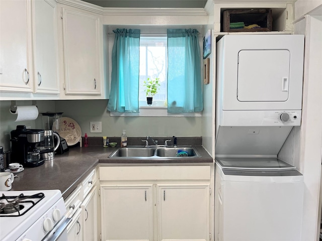 kitchen with dark countertops, stacked washer and dryer, white cabinets, and a sink