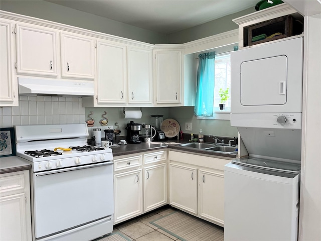 kitchen featuring under cabinet range hood, stacked washer and dryer, white gas range, white cabinetry, and a sink