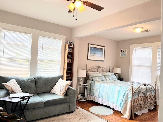 bedroom with ceiling fan, visible vents, and wood finished floors