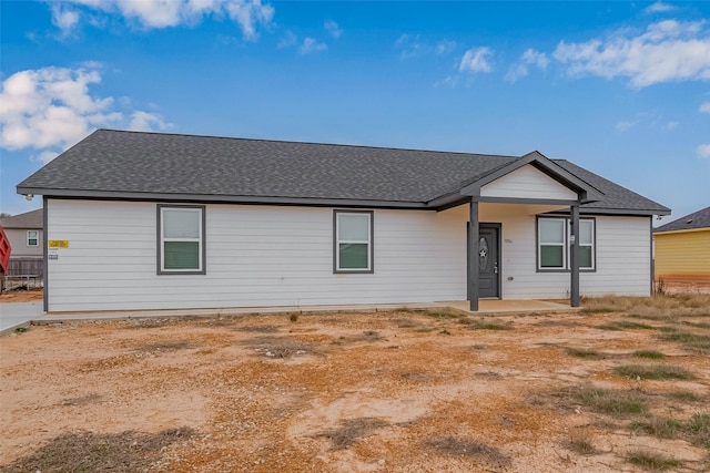 ranch-style home with a shingled roof and a patio