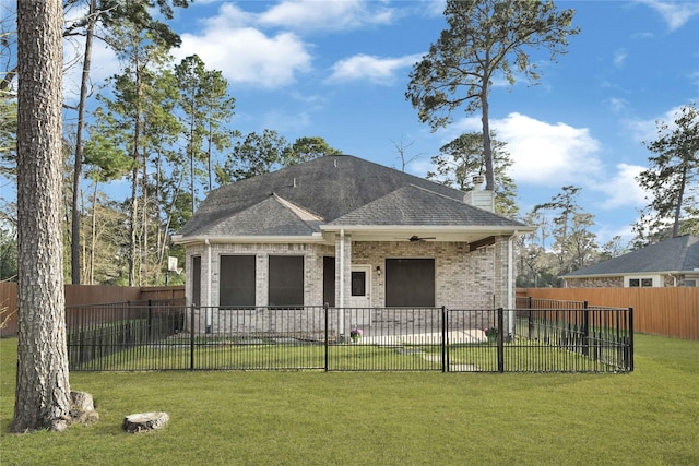 view of front facade with a front yard, a fenced backyard, brick siding, and a chimney