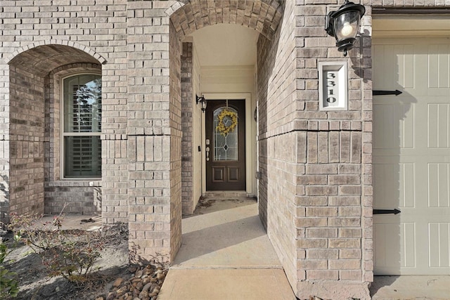 doorway to property with brick siding and an attached garage