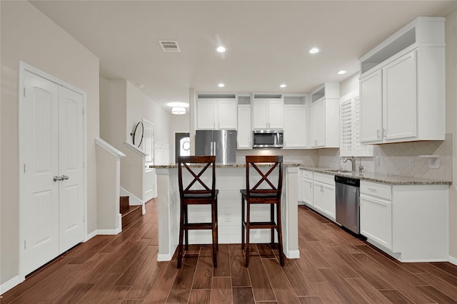 kitchen featuring visible vents, dark wood-style floors, a sink, stainless steel appliances, and backsplash