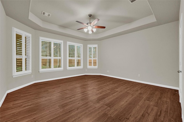 unfurnished room featuring a raised ceiling, visible vents, dark wood finished floors, and baseboards