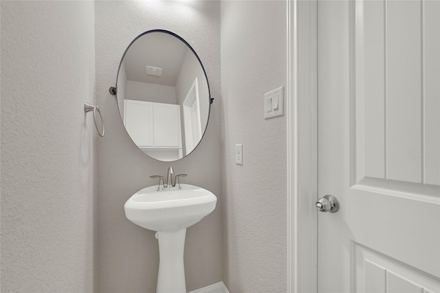 bathroom featuring a sink and a textured wall