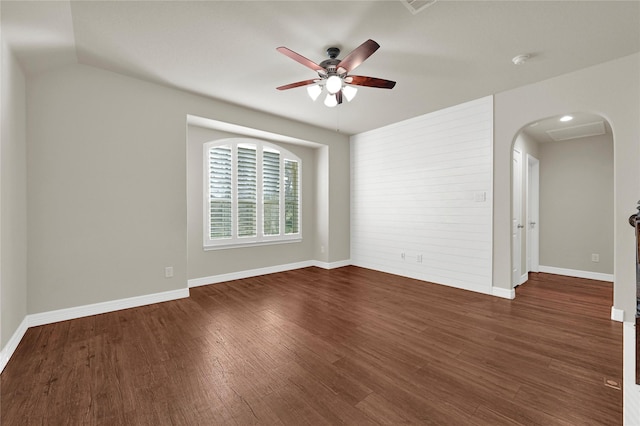 unfurnished room featuring baseboards, arched walkways, dark wood finished floors, and a ceiling fan