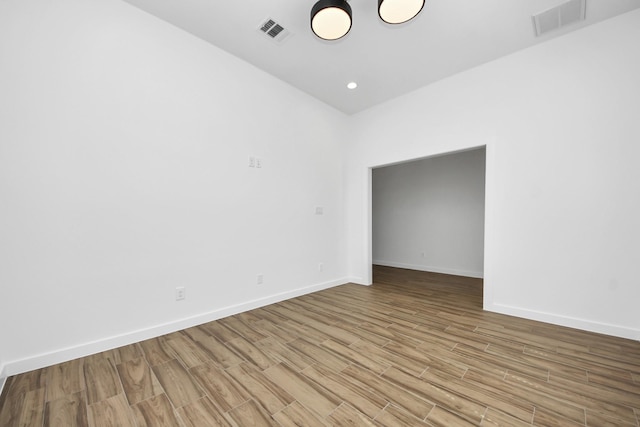 spare room with baseboards, visible vents, and wood finished floors