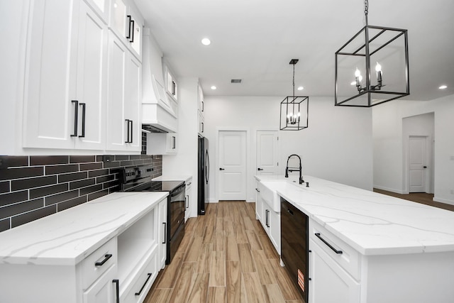 kitchen with light stone counters, tasteful backsplash, white cabinetry, light wood-type flooring, and black appliances