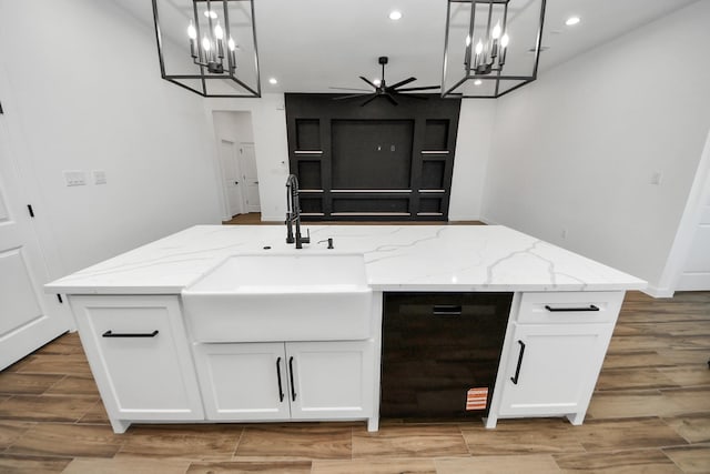 kitchen featuring light stone countertops, recessed lighting, a sink, white cabinets, and wood tiled floor