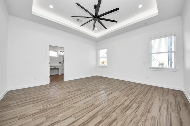 unfurnished room featuring a ceiling fan, a raised ceiling, baseboards, and wood finished floors